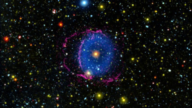 La Nebulosa del Anillo Azul consta de dos conos de gas en expansión expulsados al espacio por una fusión estelar. A medida que el gas se enfría, forma moléculas de hidrógeno que chocan con partículas en el espacio interestelar, provocando que irradien luz ultravioleta lejana. Invisible para el ojo humano, se muestra aquí como azul. Credits: NASA/JPL-Caltech/M. Seibert (Carnegie Institution for Science) / K. Hoadley (Caltech)/GALEX Team